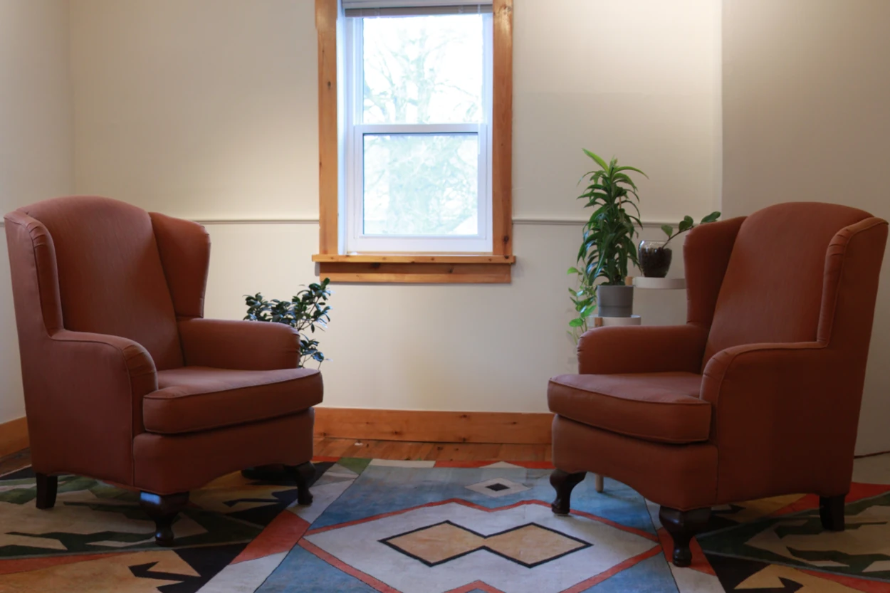 Two brown arm chairs infront of a window, inside Jen's office